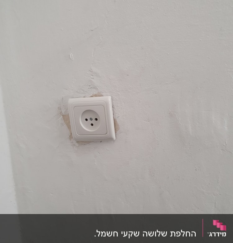 שקע חשמל בקיר לבן עם טיח מתקלף